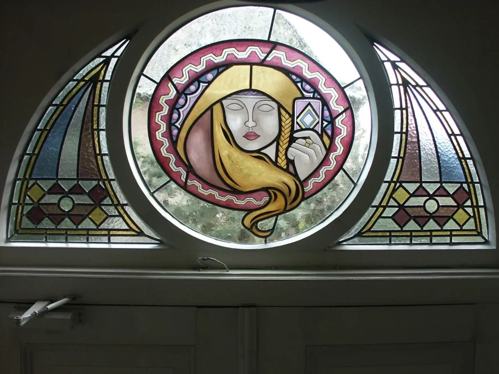 Rond brandschilderen roundel met een vrouwengezicht en gouden haar, in een groter arched raam