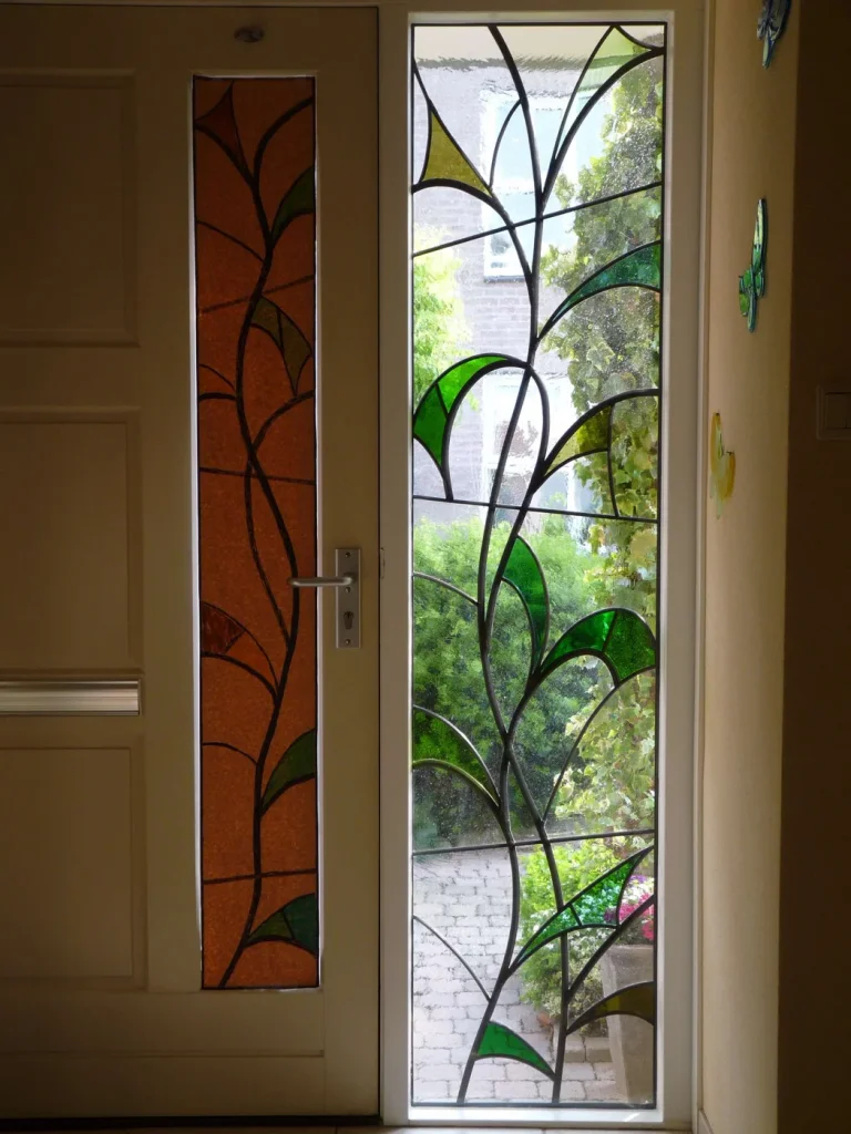 Groen art-nouveau lelie- en bladmotief in een glas-in-lood voordeur en zijlicht